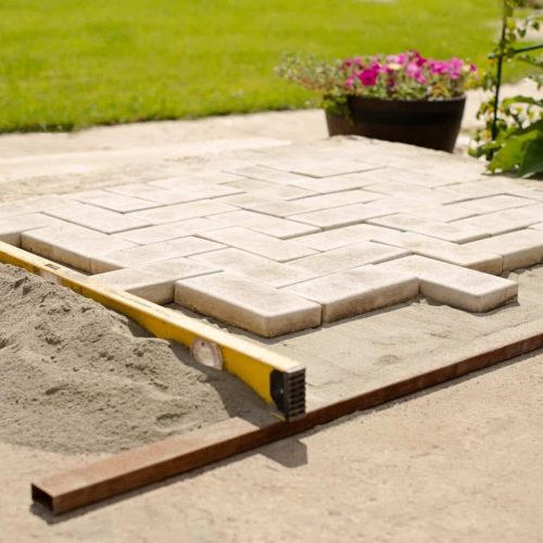 The master lays paving stones in layers. Garden brick pathway paving by professional paver worker.